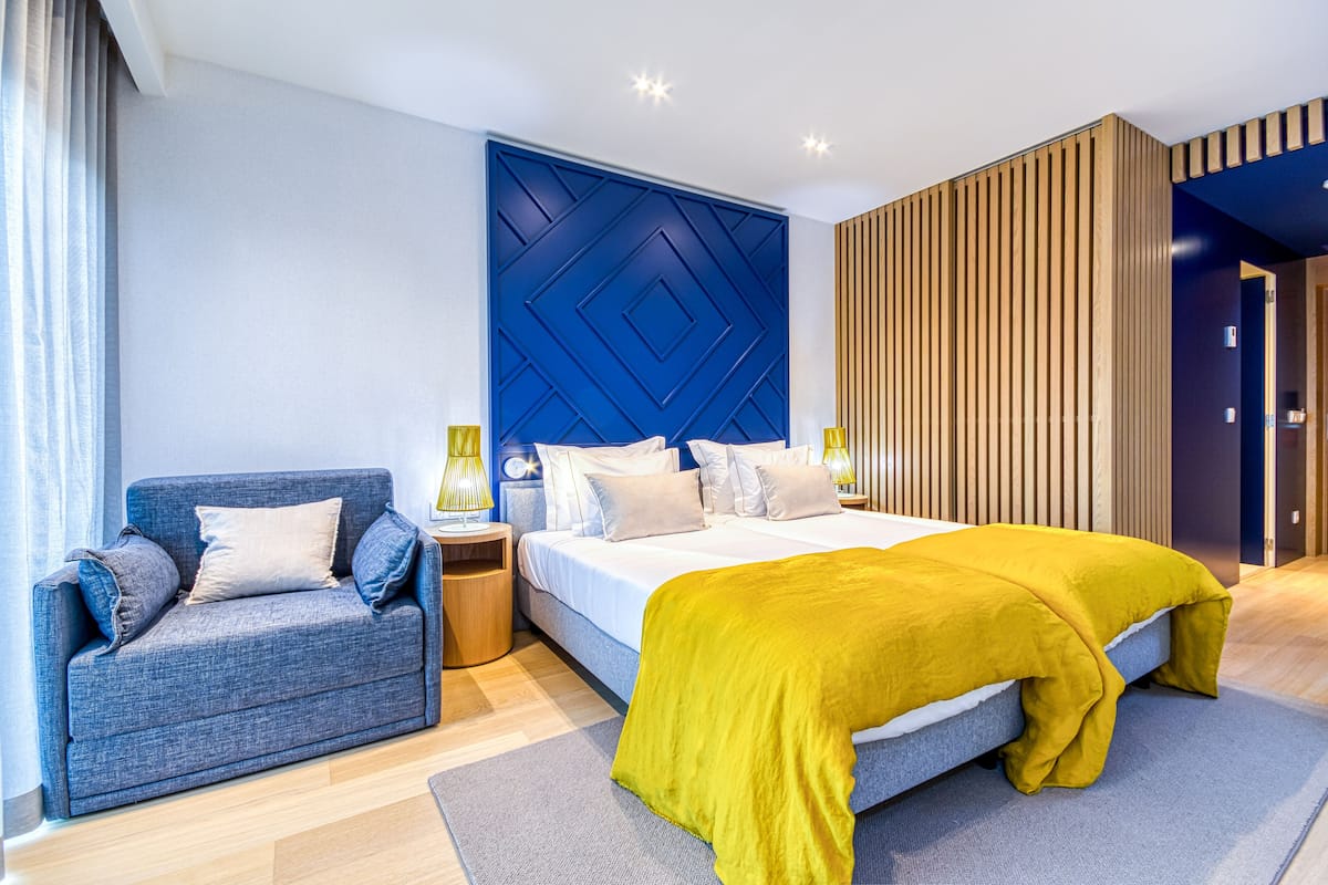 Un dormitorio moderno con cama, sofá y panel de pared de madera.