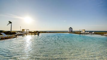 Una piscina techada, una piscina al aire libre, sombrillas