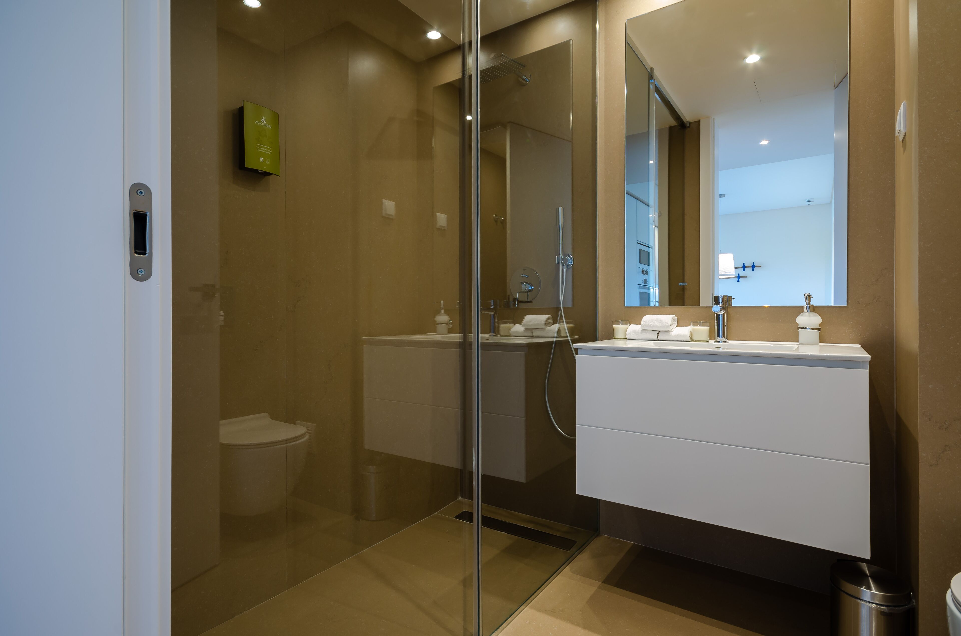 Un baño moderno con ducha envuelta en vidrio, un lavabo blanco y un espejo grande.