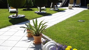 A garden pathway with potted plants and a small seating area with chairs. - Hotel zur Fischerklause (Butjadingen)