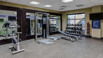A gym with cardio equipment, weightlifting stations, and dumbbells.