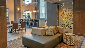 A modern lounge area with a sofa, chairs, a bar, and a patterned rug. - Hampton Inn & Suites San Jose Airport (San Jose)