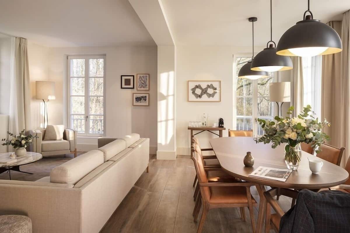 A modern living room with a sofa, a dining table with chairs, and pendant lighting.