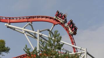 A roller coaster with passengers in red cars.