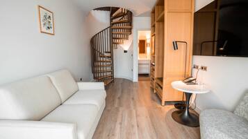 Una sala de estar moderna con una escalera en espiral, un sofá blanco y un aparador de madera.