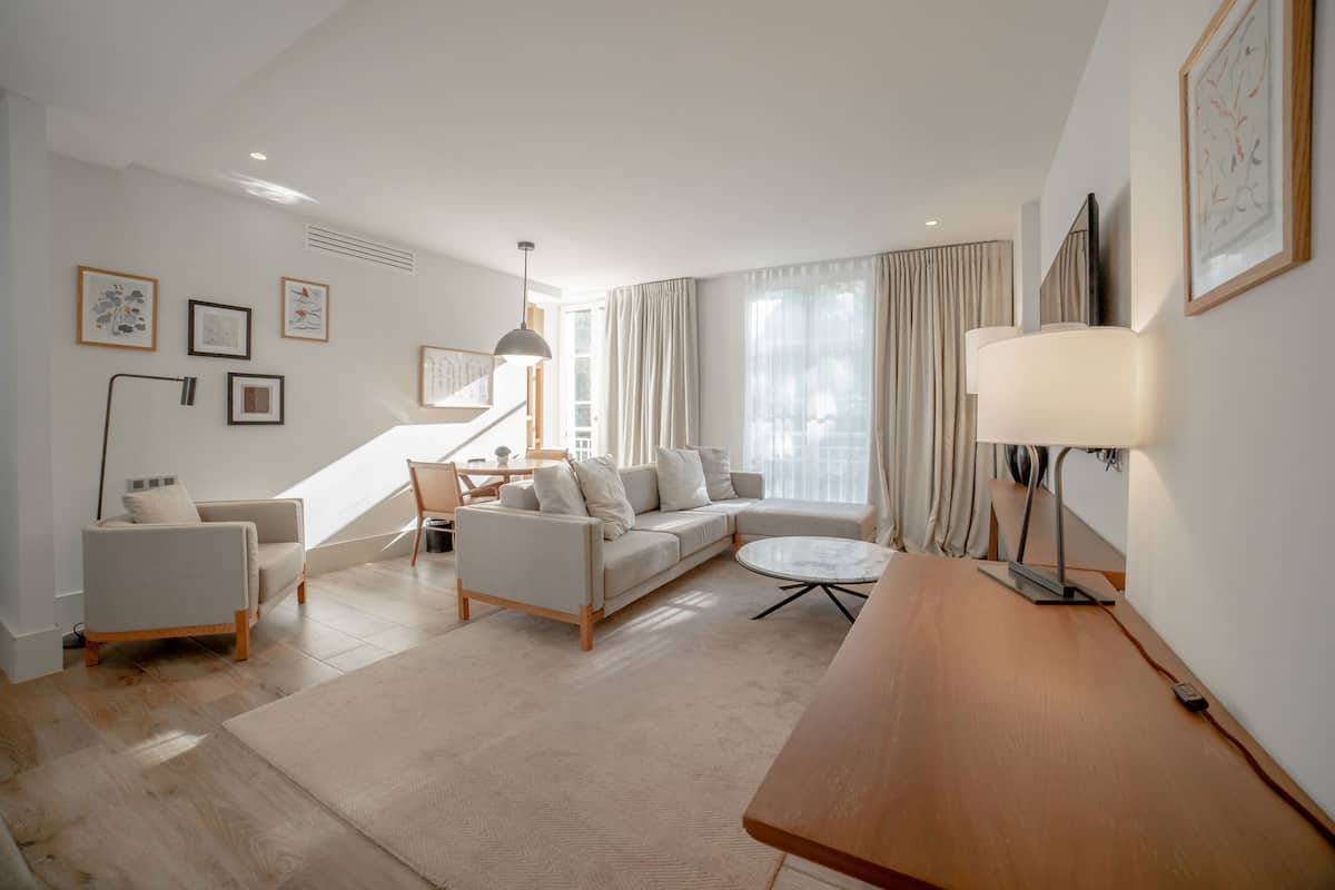 A modern living room with a sofa, armchairs, a coffee table, and a lamp.