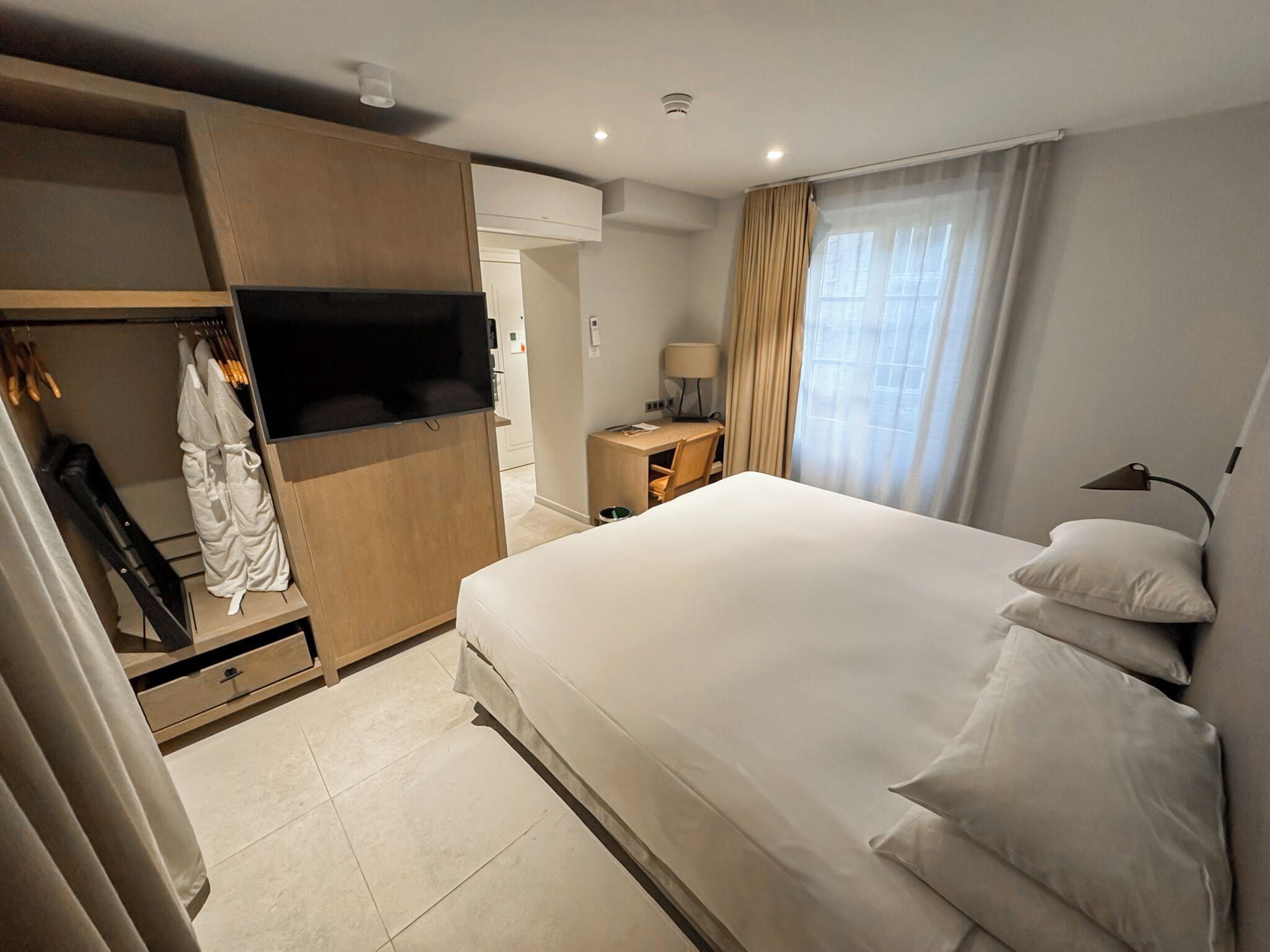 A hotel room with a bed, a TV, a desk, and a wardrobe.