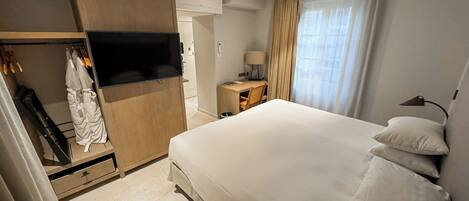 A hotel room with a bed, a TV, a desk, and a wardrobe.