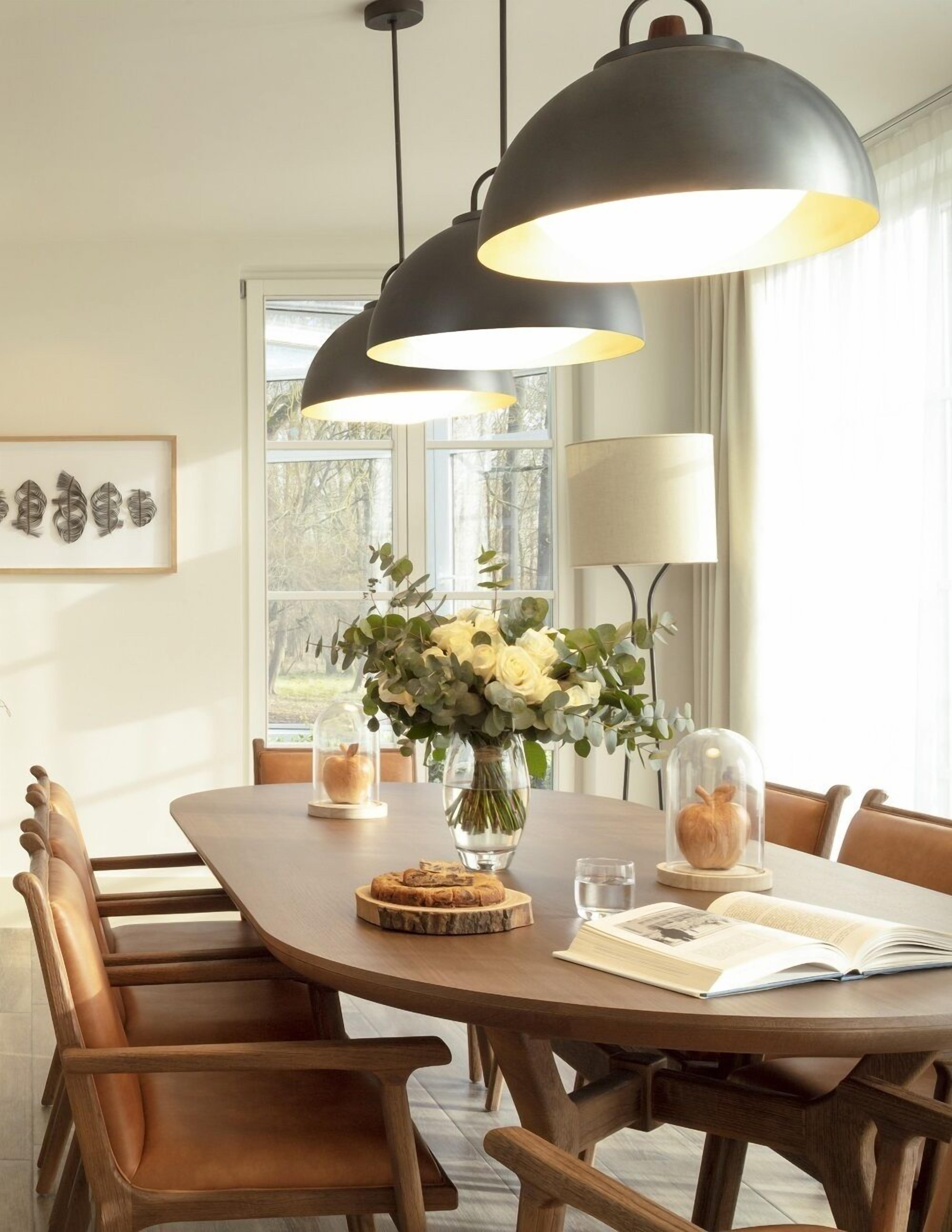 A dining area with a wooden table, chairs, a vase of flowers, and a book.
