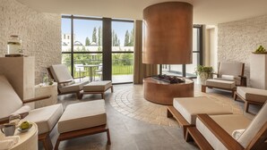 Ein moderner Lounge-Bereich mit Steinwand, großen Fenstern und einem zentralen Kamin.