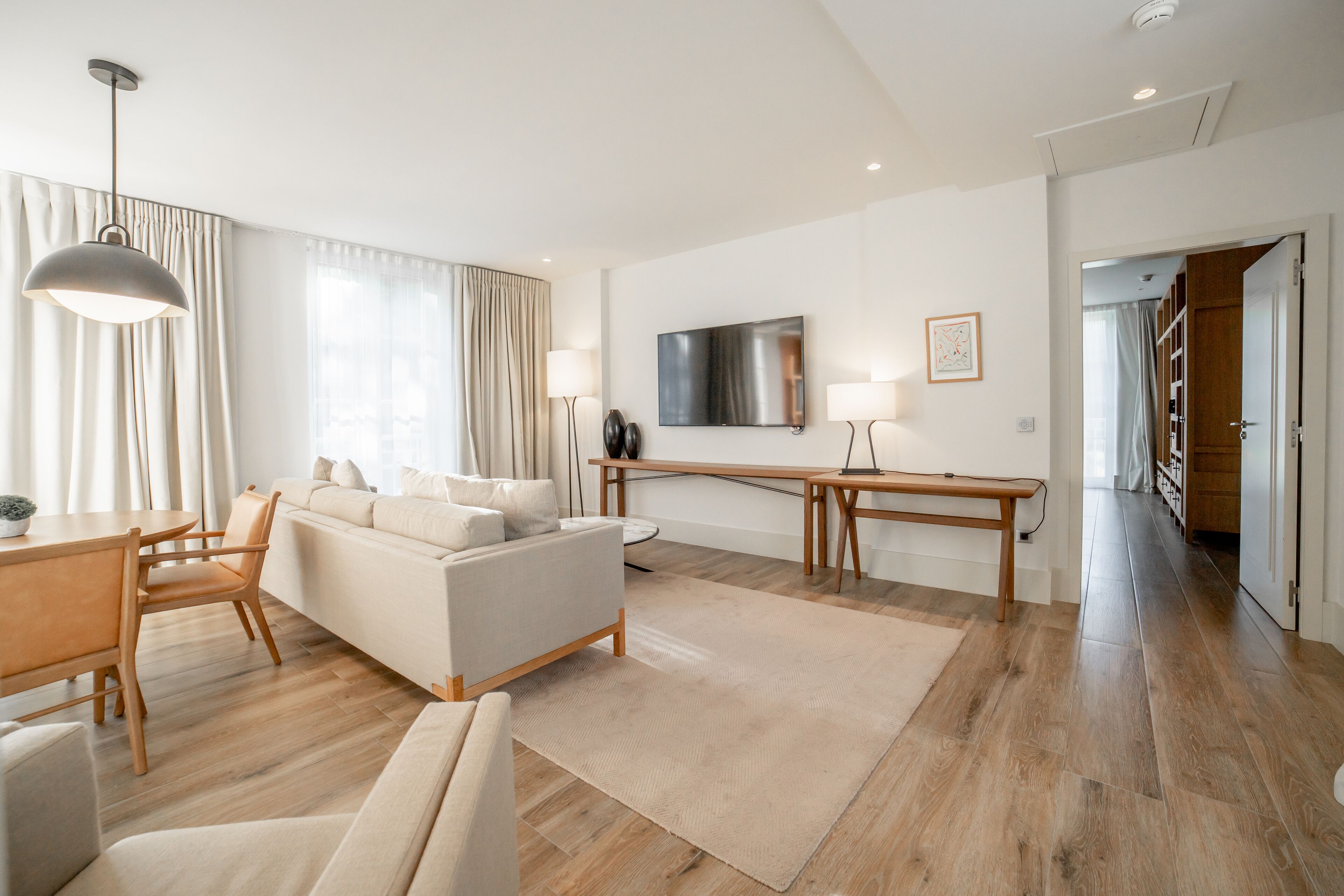 A modern living room with a sofa, a dining table, and a TV.