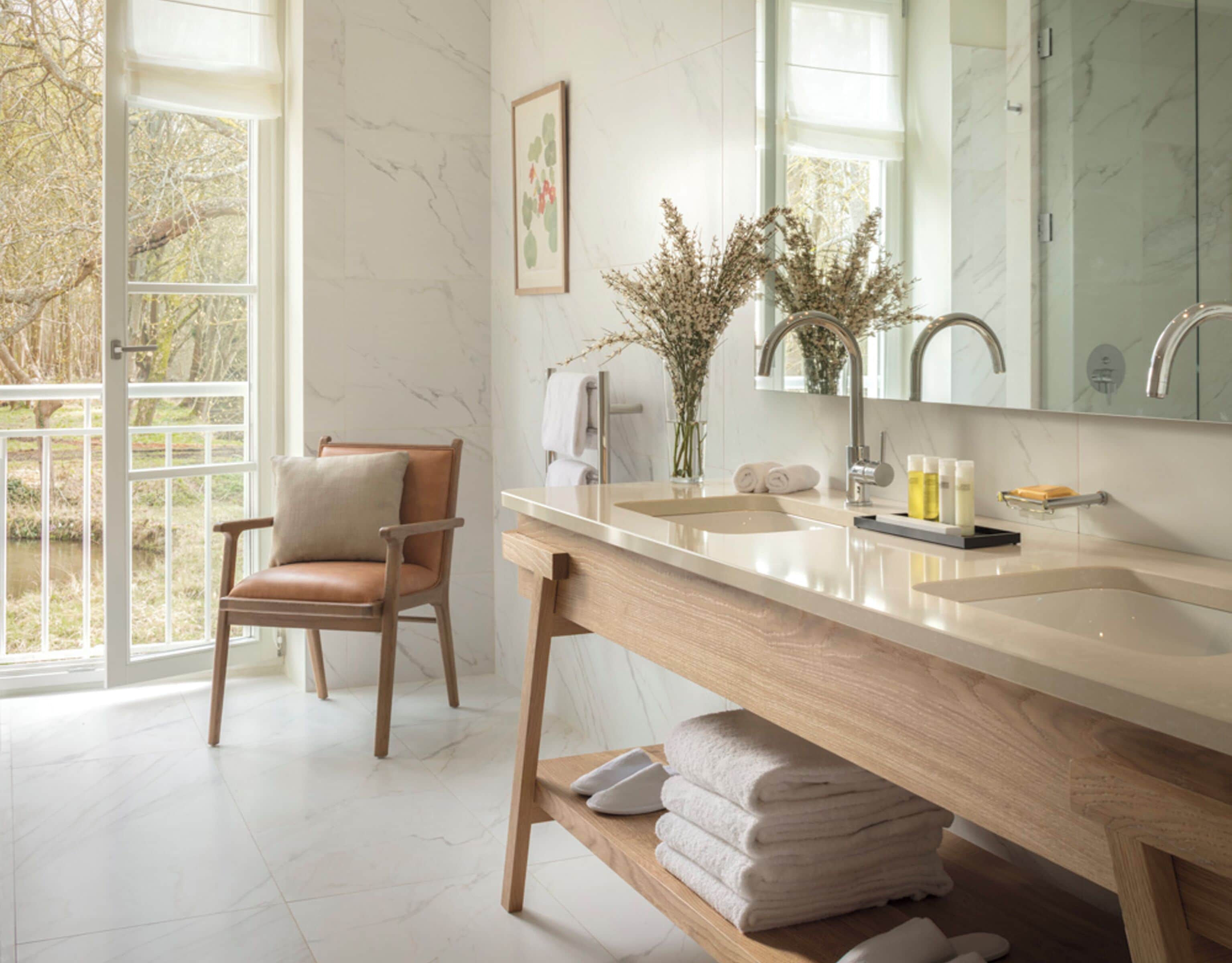 Un bagno con un mobile bagno in legno, uno specchio grande, un lavandino e una sedia.