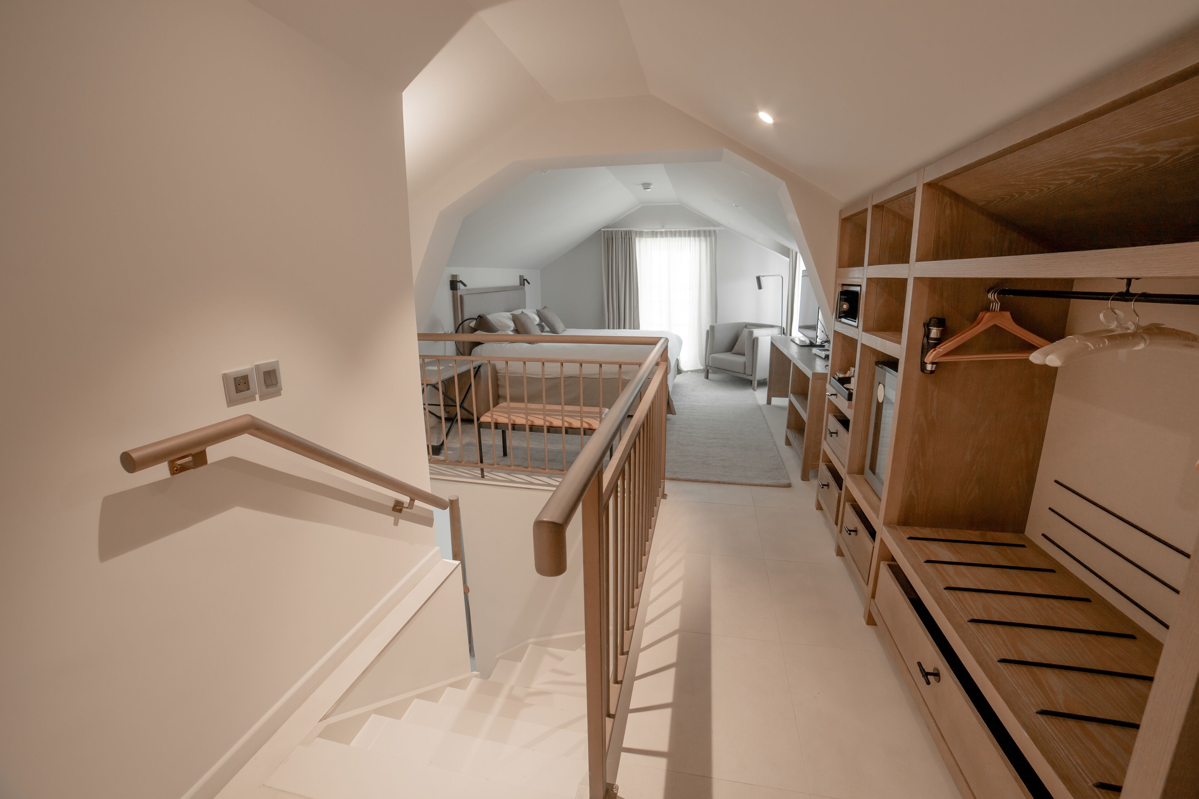 A spacious bedroom with a large closet, a wooden bed frame, and a view to a living area.