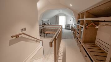 A spacious bedroom with a large closet, a wooden bed frame, and a view to a living area.