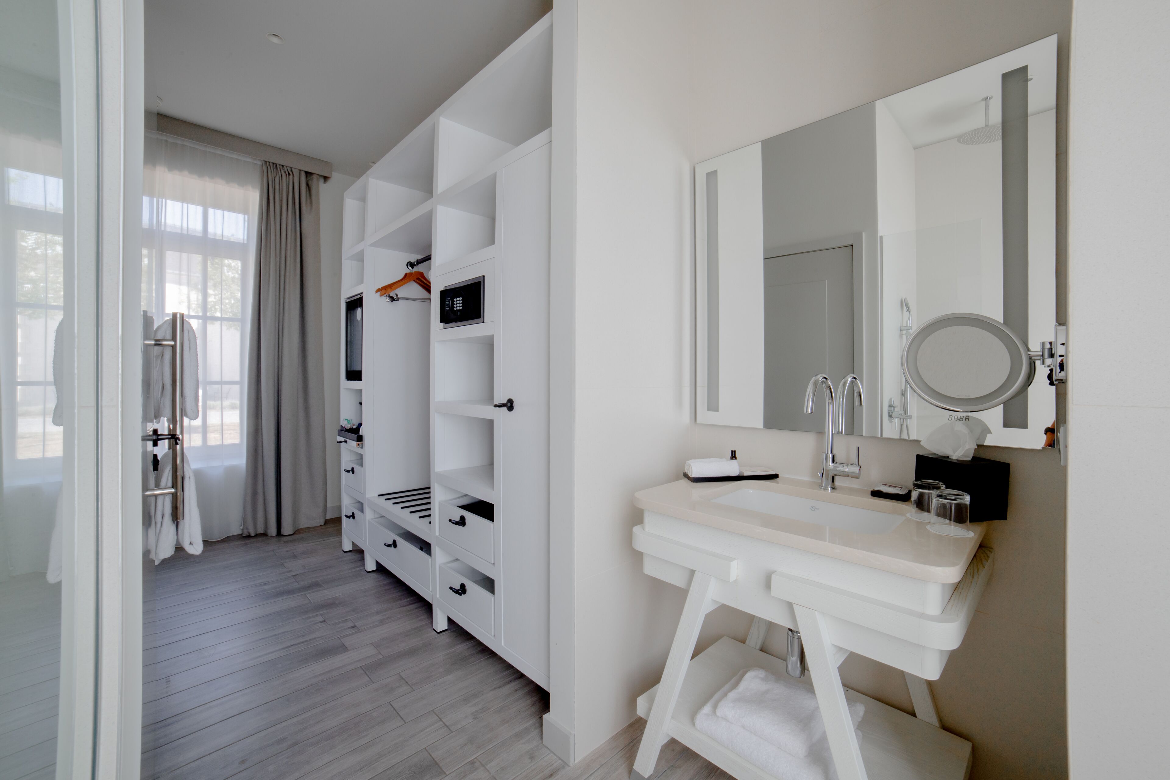 A modern bathroom with a white vanity, a large mirror, and built-in shelves.