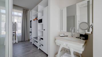 A modern bathroom with a white vanity, a large mirror, and built-in shelves.
