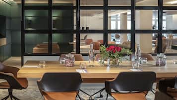 Een moderne vergaderruimte met een lange tafel, lederen stoelen en grote ramen.