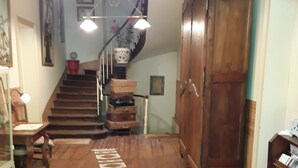 Een trap met houten treden die uitkomt op een plateau, een houten kast en een vloerkleed met een patroon.