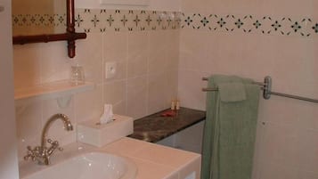 Casa de banho com lavatório, espelho, porta-toalhas e azulejos estampados.