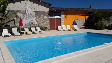 Una piscina al aire libre de temporada, sillones reclinables de piscina