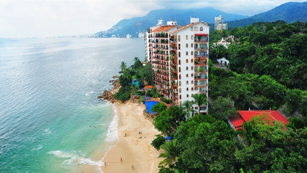 A coastal hotel with multiple balconies, a pool, and a beach view. - Beach Front Girasol Sur Apartments (Puerto Vallarta)