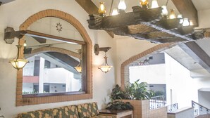 A spacious lobby with a high ceiling, exposed wooden beams, a large mirror, and a seating area with a floral sofa. - Beach Front Girasol Sur Apartments (Puerto Vallarta)