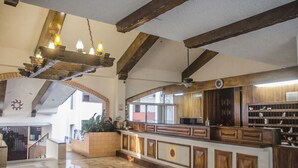 A spacious lobby with a wooden reception desk, a ceiling fan, and a large window allowing natural light. - Beach Front Girasol Sur Apartments (Puerto Vallarta)