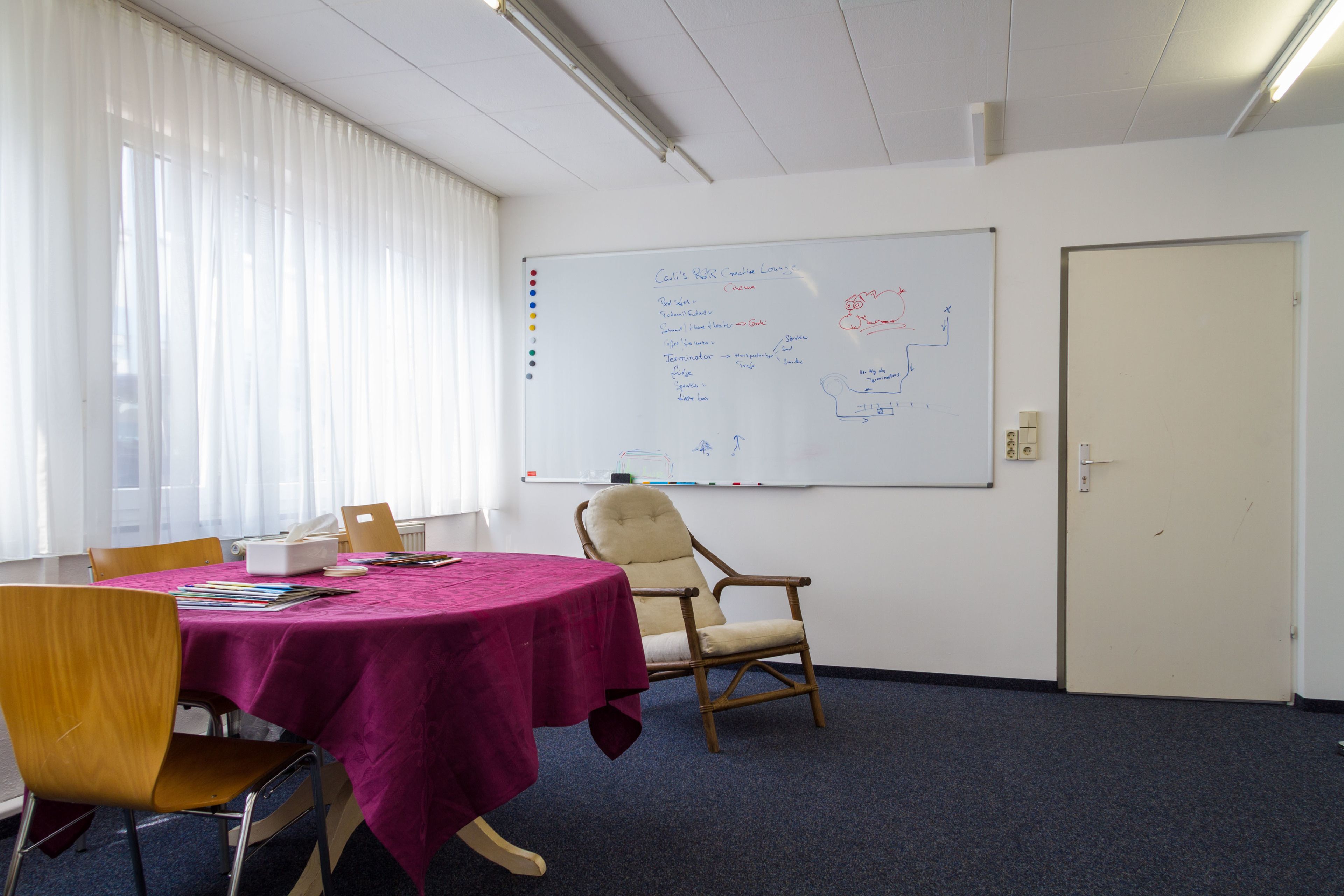 A conference room with a whiteboard, a table with a purple tablecloth, and chairs.