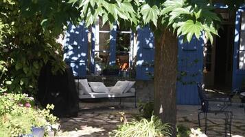 A patio area with a white outdoor sofa, a tree, and potted plants.