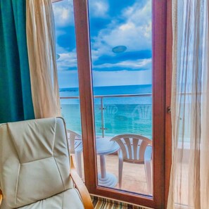 A balcony with a view of the sea, a white chair, and a small table. - Mirage Hotel (Nessebar)