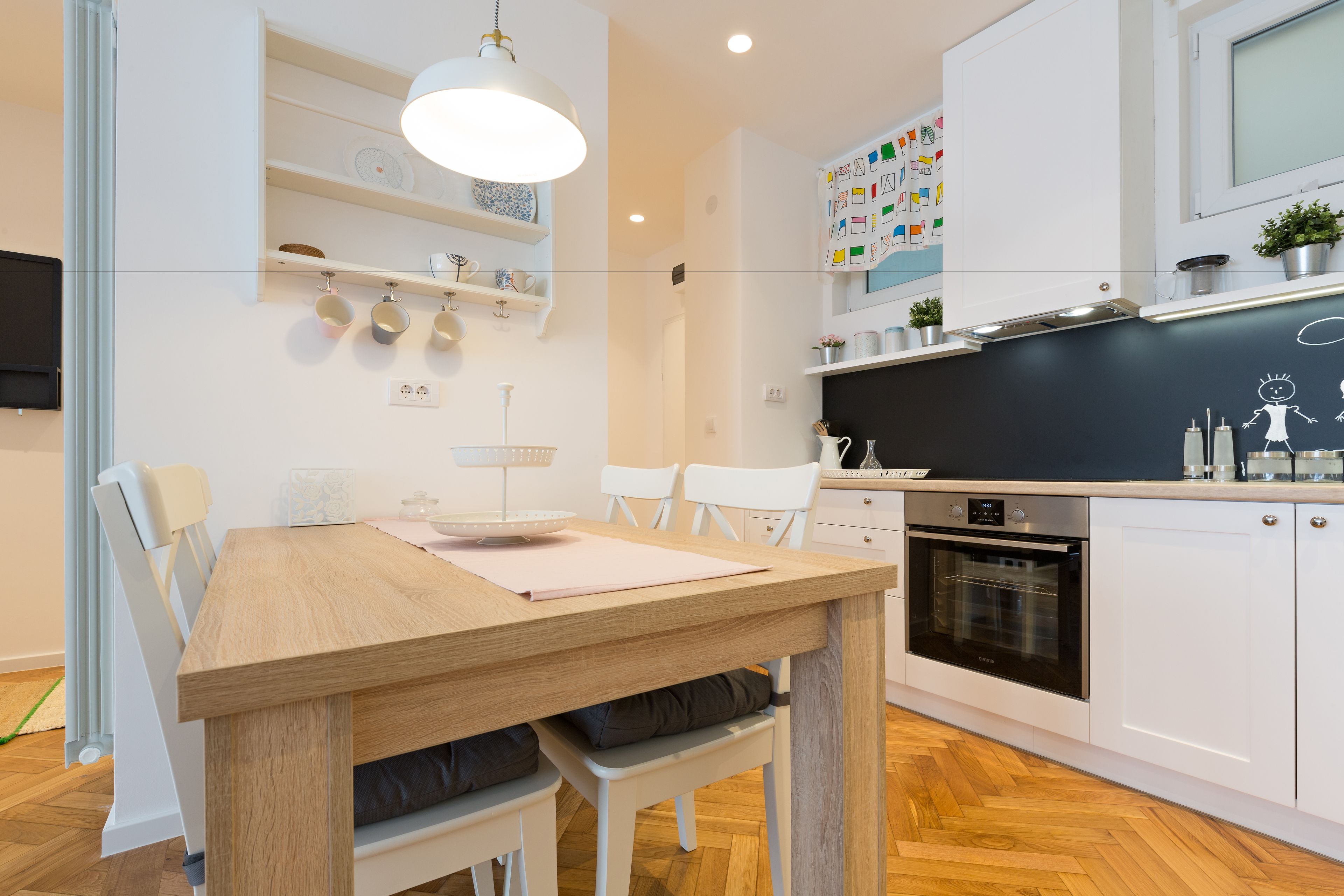 Eine moderne Küche mit weißen Schränken, einem Holzespeisetisch und einem eingebauten Backofen.