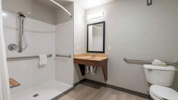 A bathroom with a shower, sink, toilet, and a mirror.