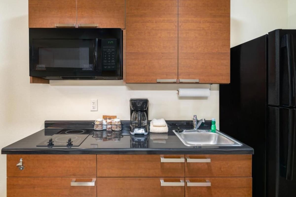 A compact kitchen with a microwave, coffee maker, and sink.
