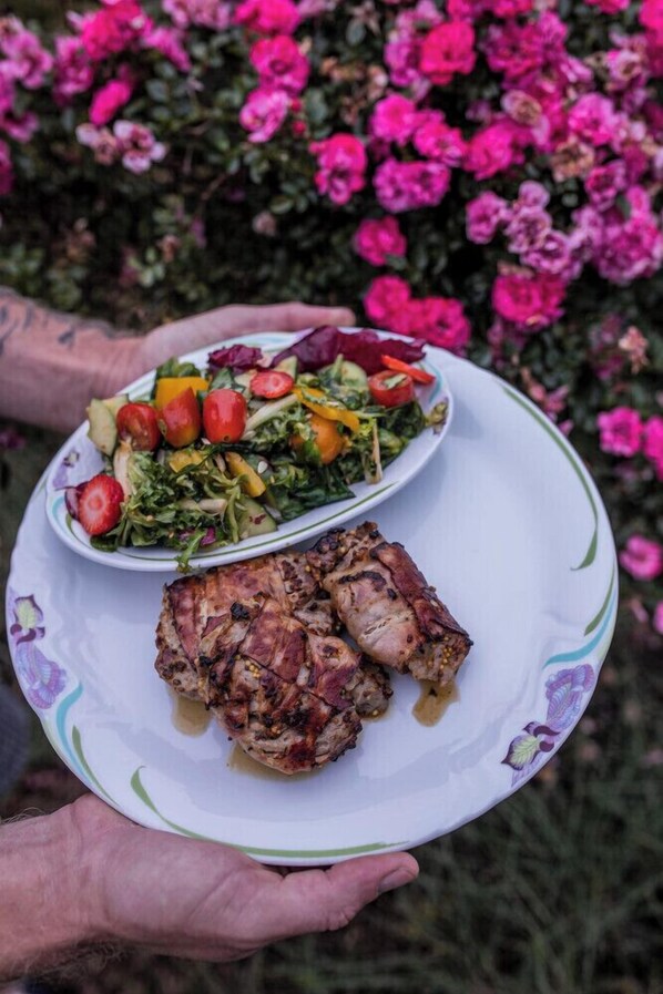A plate with grilled meat and a salad, held by a person with tattoos. - SPA Pod javory (Nejdek)