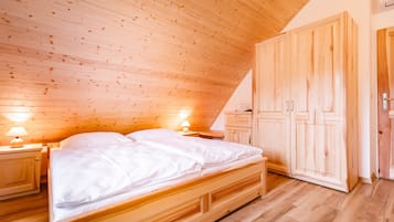 Ein Zimmer mit Holzwänden, einem Bett, Nachttischen und einem Kleiderschrank.