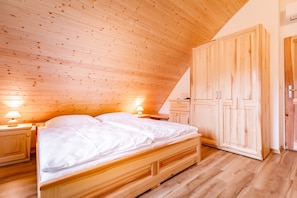 A wooden-paneled room with a bed, nightstands, and a wardrobe. - SPA Pod javory (Nejdek)