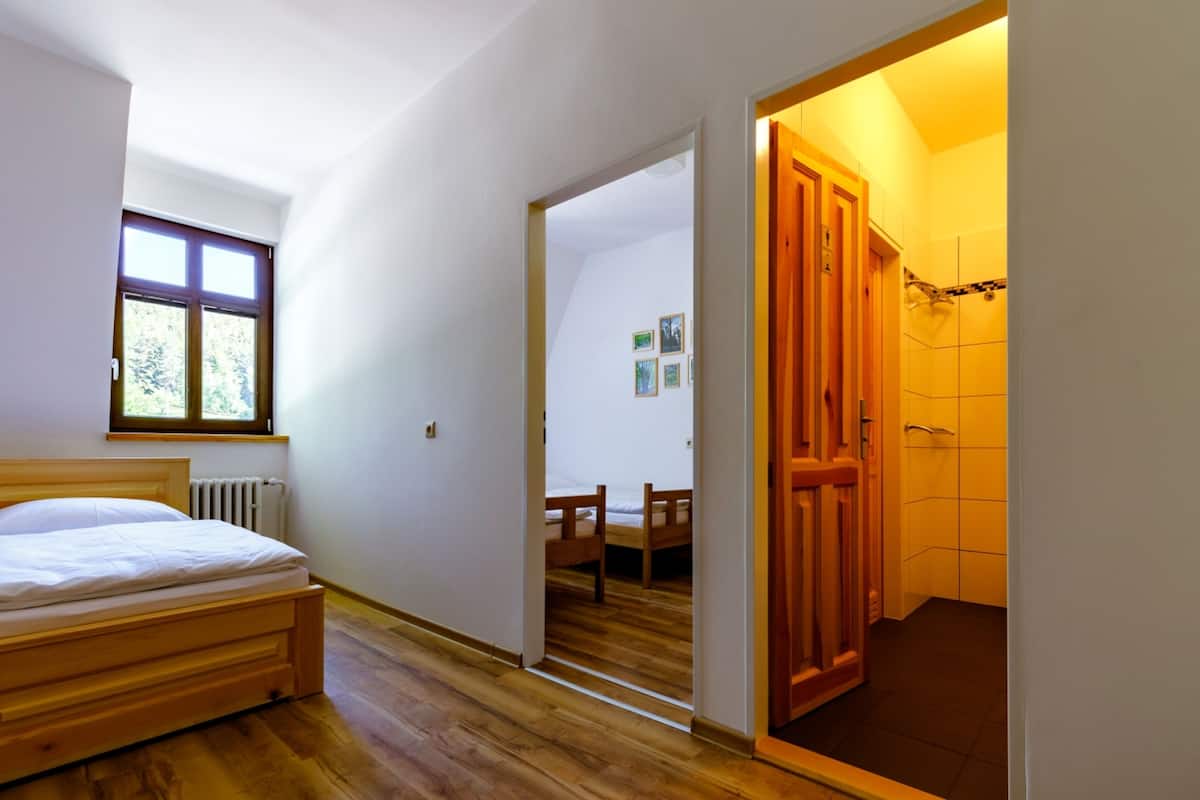 Un dormitorio con una cama de madera, una ventana y una puerta que da a un baño.
