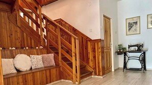Eine Holztreppe mit einer Sitzbank unten, einer Nähmaschine auf einem Tisch und einer Tür im Hintergrund.
