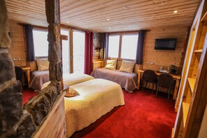 A wooden cabin-style room with two beds, a desk, and a TV. - Chalet Monte Bianco (Tignes)