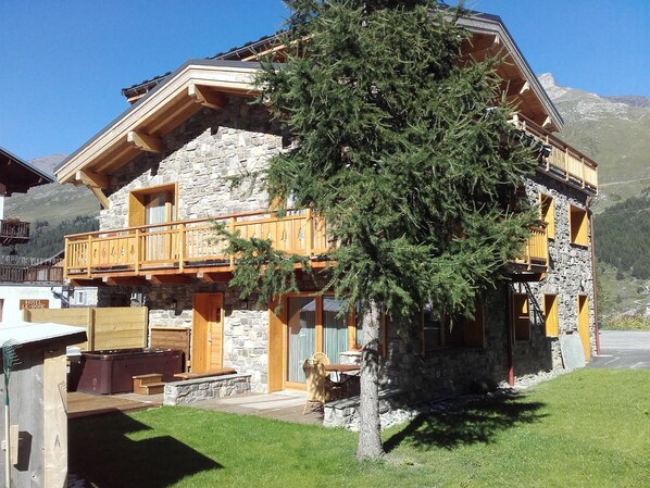 A stone building with a wooden balcony, a hot tub, and a sign that reads "HOTEL LE-DONE". - Chalet Monte Bianco (Tignes)