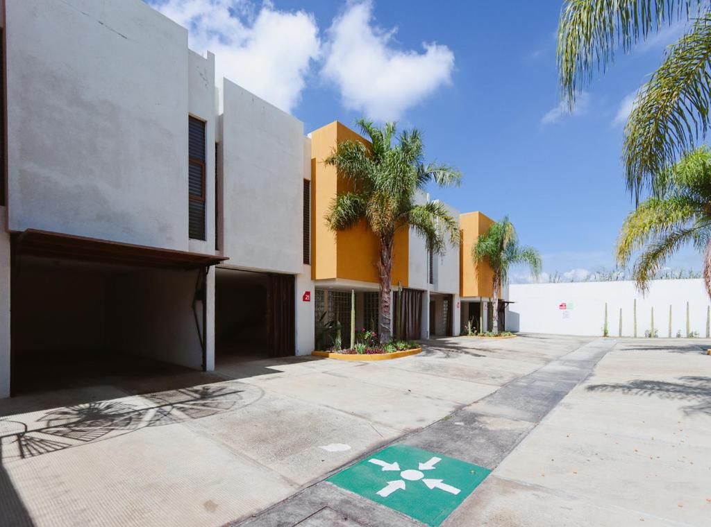 Un área de estacionamiento con carril bici, palmeras y edificios modernos bajo un cielo despejado.