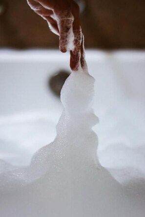 Una mano sostiene un vaso transparente con un líquido, posiblemente agua, que refleja la imagen de una persona.