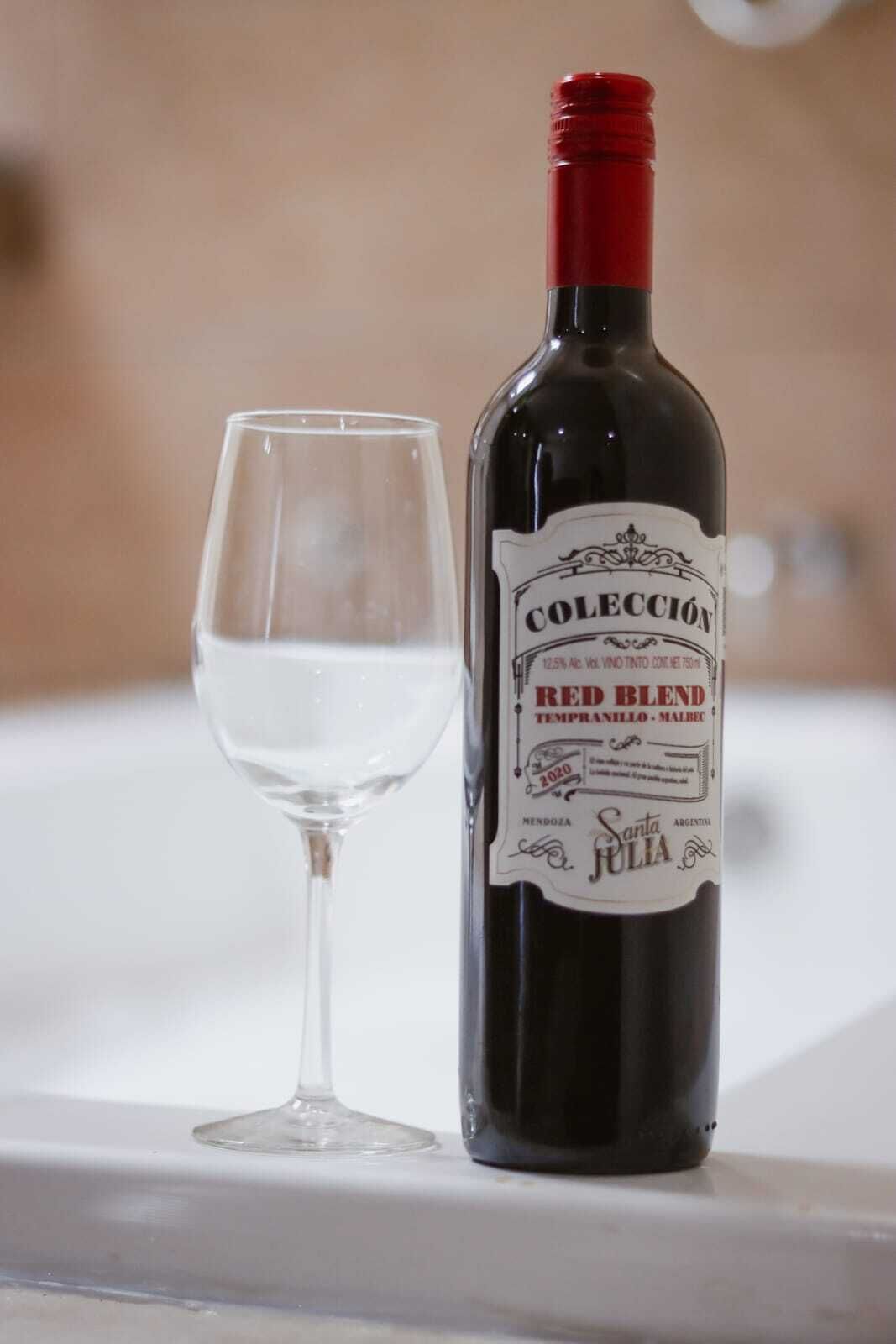 A bottle of red blend wine next to an empty wine glass on a table.