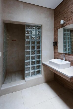 Un baño con ducha, lavamanos y espejo.