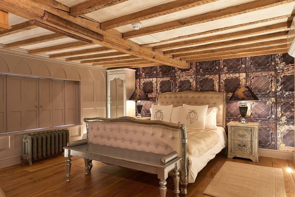A bedroom with a bed, a bench, a nightstand, and a radiator.