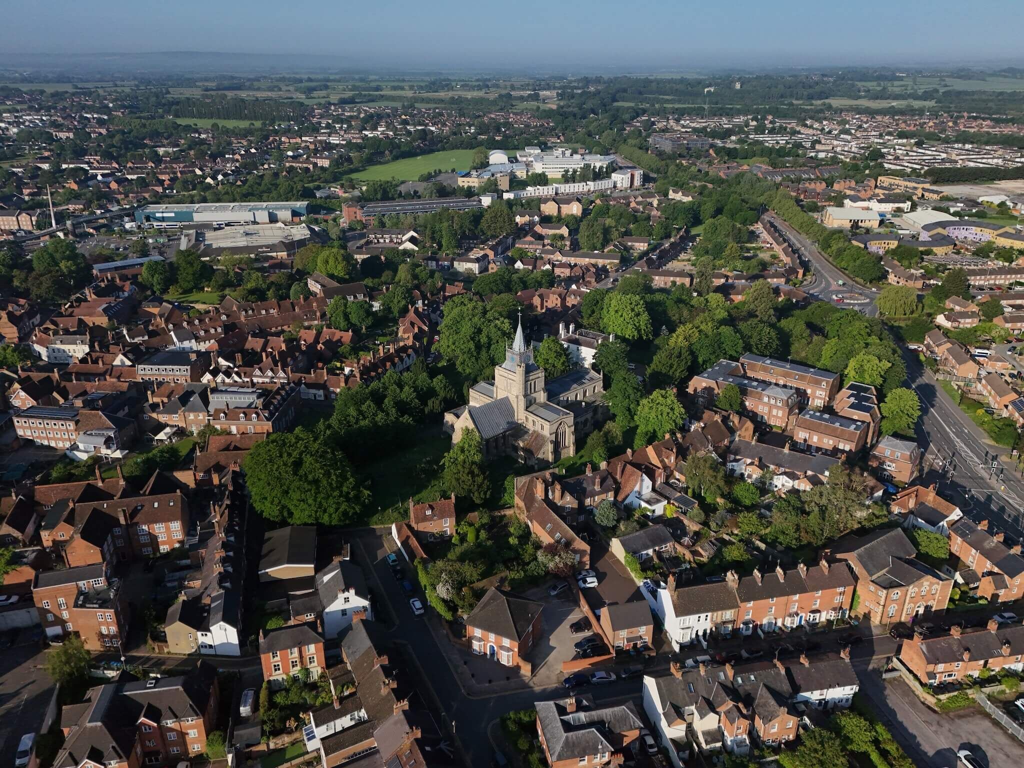 An aerial view of a town with a prominent church, residential areas, and a large industrial building.