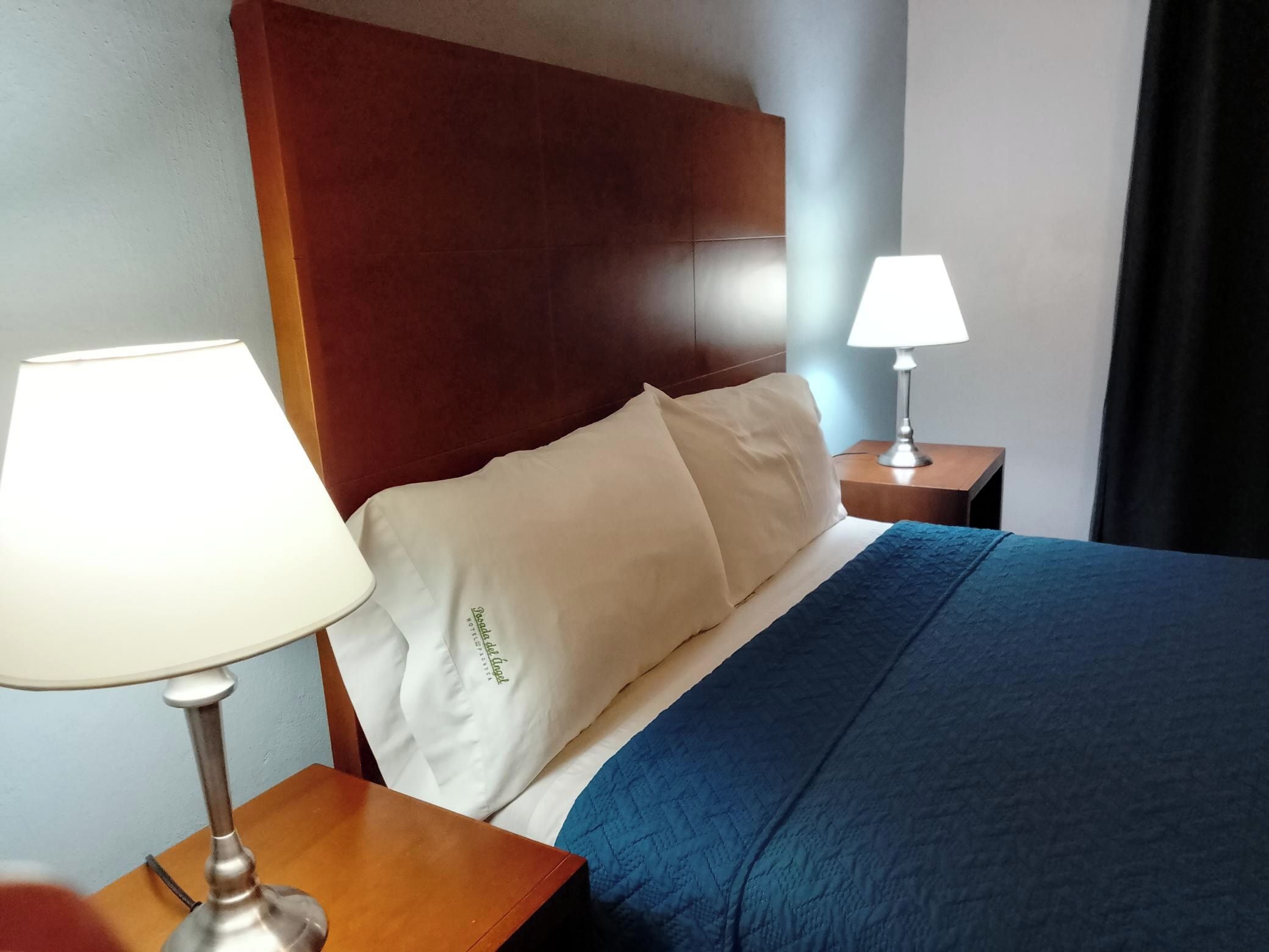Une chambre d’hôtel avec un lit, une table de chevet avec une lampe et une tête de lit.