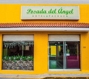 Un hotel llamado Posada del Ángel, con fachada amarilla y un letrero sobre la entrada.