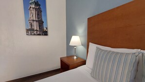A hotel room with a bed, a nightstand with a lamp, a framed picture on the wall, and a wooden headboard. - Posada del Ángel (Mineral de la Reforma)