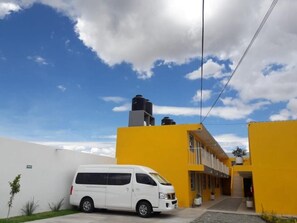 Una furgoneta blanca aparcada davant d'un edifici groc sota un cel serè.